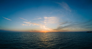 Serene Ocean Sunset With Golden Sunlight Reflecting On Calm Blue Waters And Soft Clouds HD wallpaper