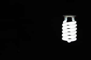 Illuminated Spiral CFL Light Bulb Against a Pitch Black Background HD wallpaper