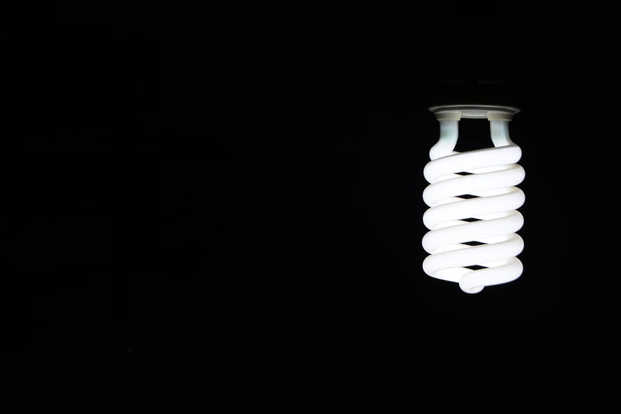 Illuminated Spiral CFL Light Bulb Against a Pitch Black Background HD wallpaper