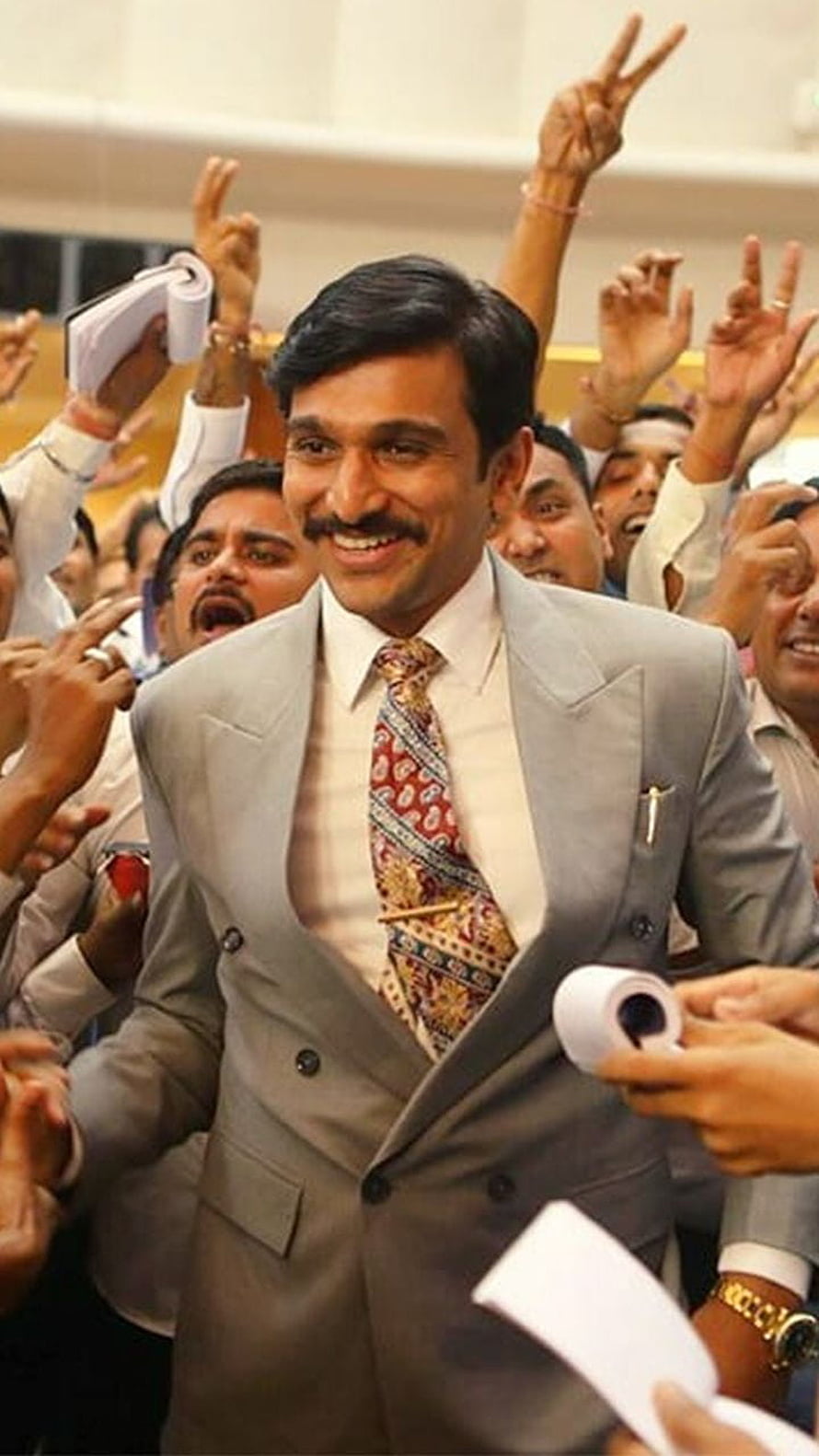 Allu Arjun in a grey suit smiling amidst a crowd of cheering fans holding papers HD phone wallpaper