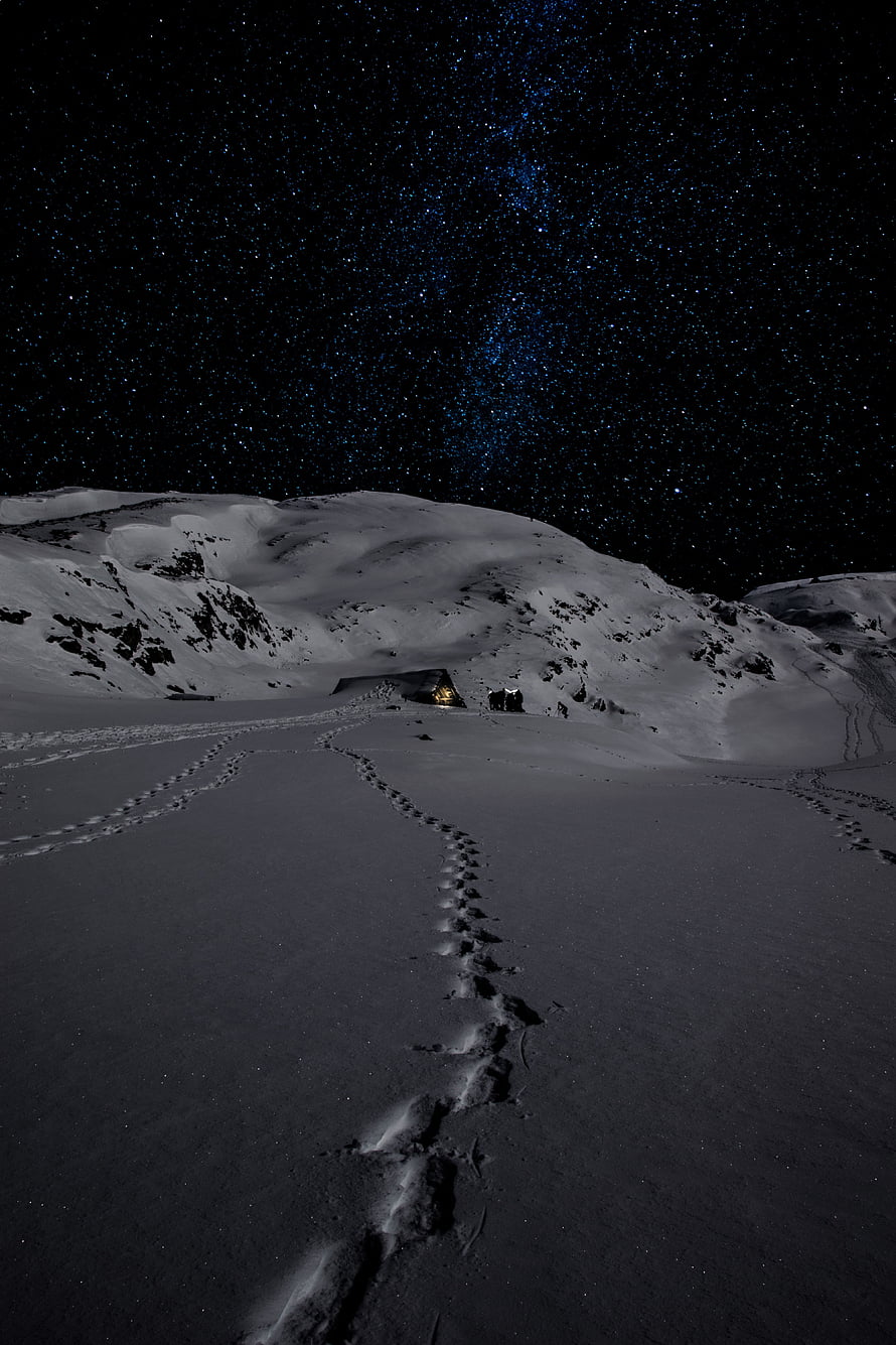 Snowy Mountain Trail Under the Milky Way with Footprints Leading to a Glowing Tent HD phone wallpaper
