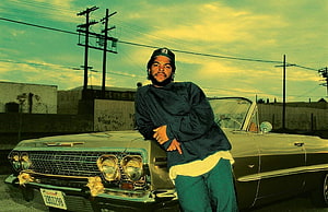 Ice Cube Leaning Against a Classic Car in a Vintage Street Scene HD wallpaper