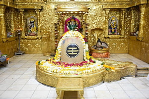 Golden Shiva Lingam Temple Interior with Flower Garlands and Deities HD wallpaper