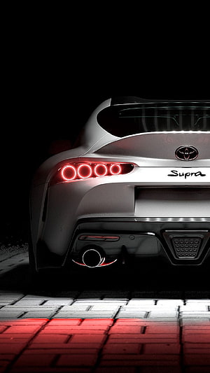 Rear View of a White Toyota Supra with Glowing Red Taillights on a Brick Road at Night HD phone wallpaper