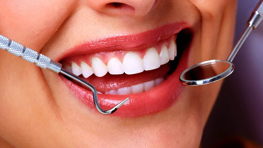 Close-up of a bright smile during a dental checkup with professional instruments HD wallpaper