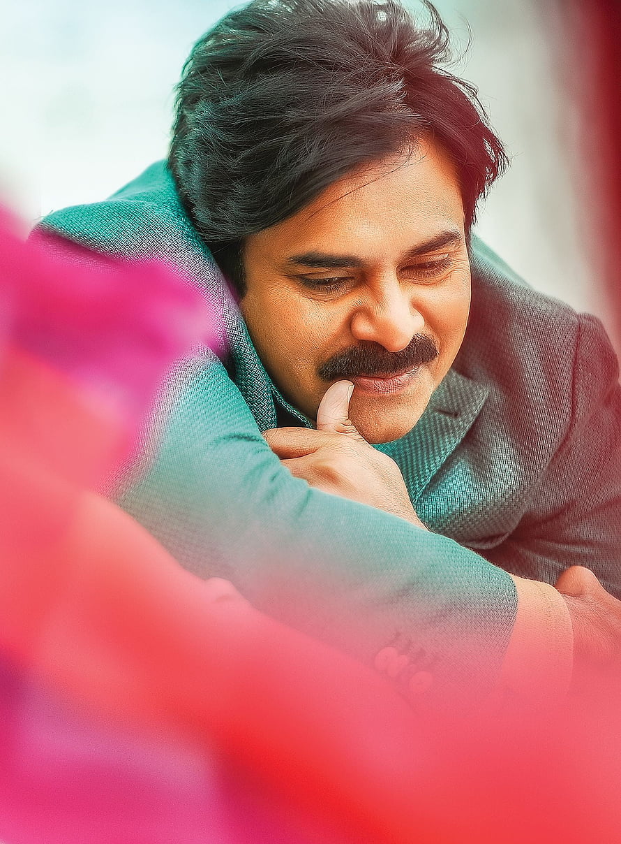 Pawan Kalyan in a teal suit with a contemplative expression and soft pink foreground bokeh HD phone wallpaper