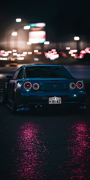 Nissan GT-R R34 Rear View at Night with Neon City Lights and Wet Asphalt Reflections HD phone wallpaper