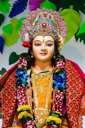 Vibrant Hindu Goddess Statue Adorned with Gold Jewelry and Floral Garlands HD phone wallpaper