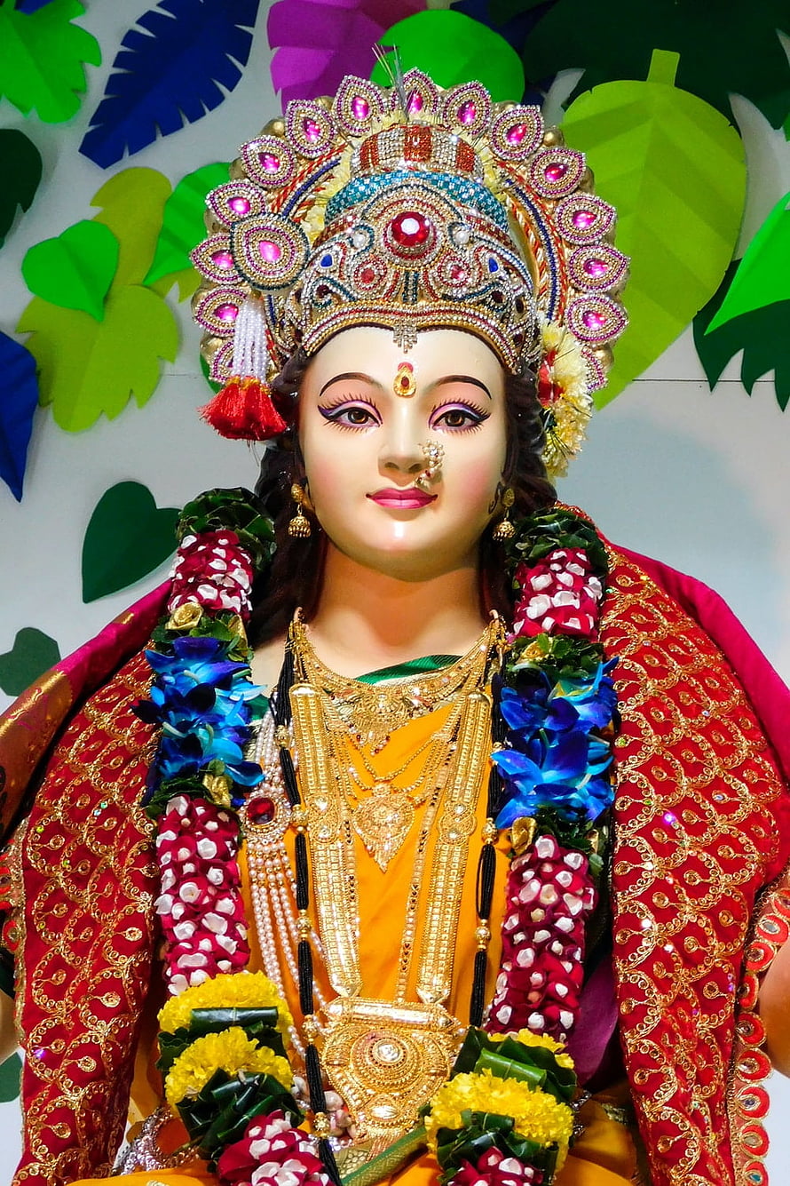 Vibrant Hindu Goddess Statue Adorned with Gold Jewelry and Floral Garlands HD phone wallpaper