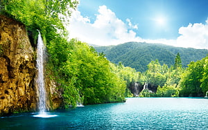 Serene Waterfall Cascading Into Turquoise Lake Surrounded By Lush Green Forest HD wallpaper