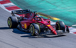 Scuderia Ferrari F1-75 race car speeding on track with Charles Leclerc in stylized vector art HD wallpaper