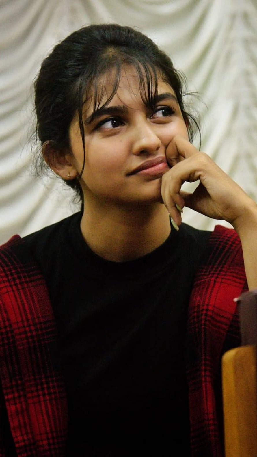 Mamitha Baiju in a red plaid jacket with a thoughtful expression HD phone wallpaper
