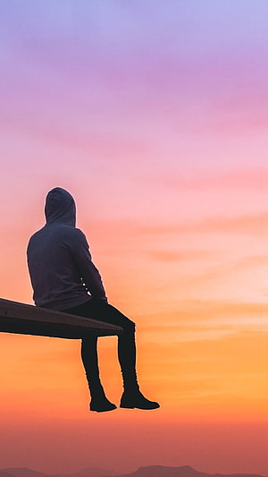 Silhouette of a person in a hoodie sitting on a ledge against a vibrant sunset sky HD phone wallpaper