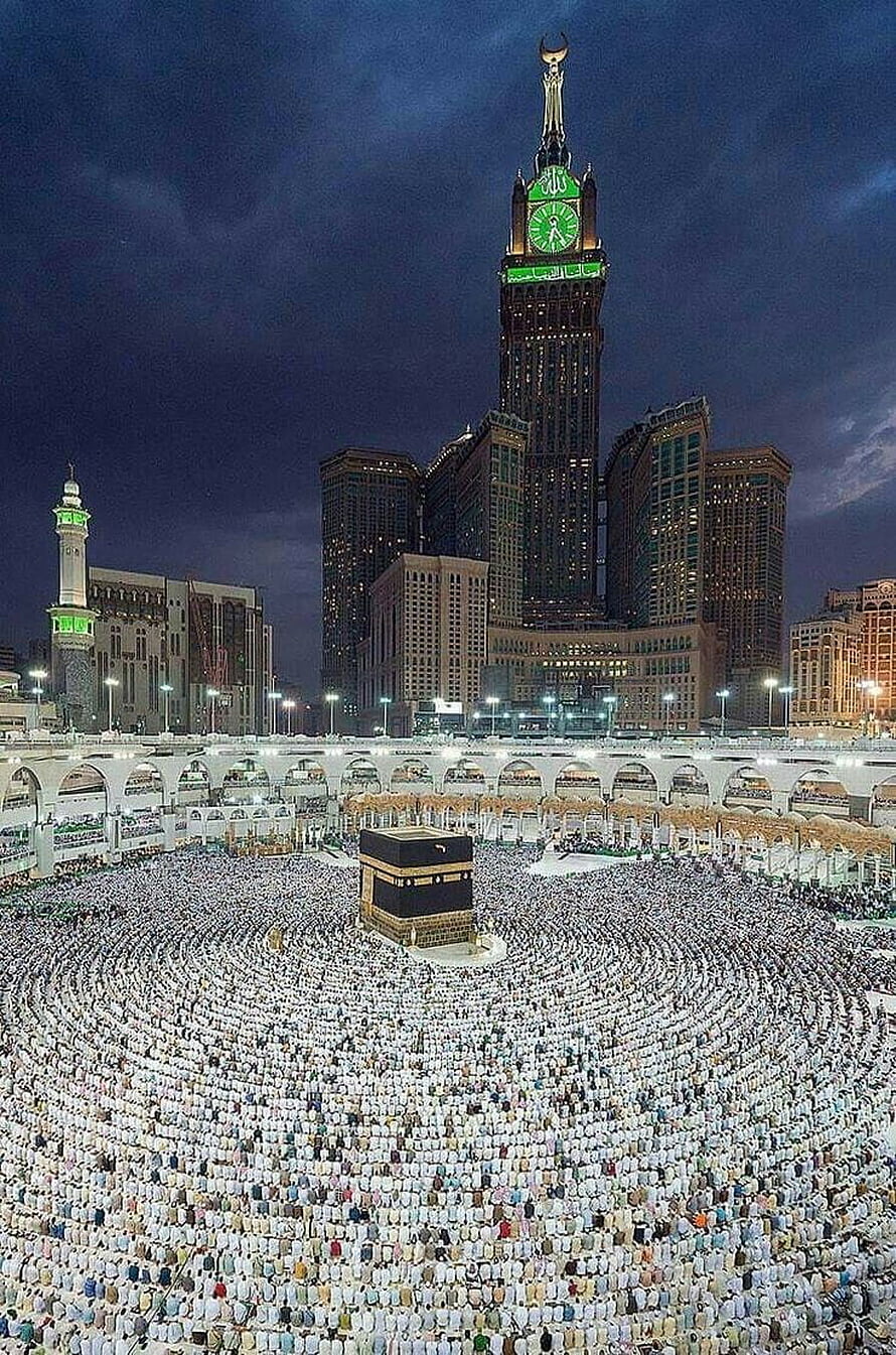 Night view of the Kaaba in Mecca with the Abraj Al Bait clock tower and massive crowd of pilgrims praying HD phone wallpaper