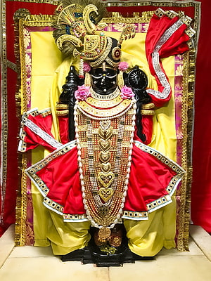 Black Idol of Lord Krishna Adorned with Gold Jewelry and Red Silk Garments HD phone wallpaper