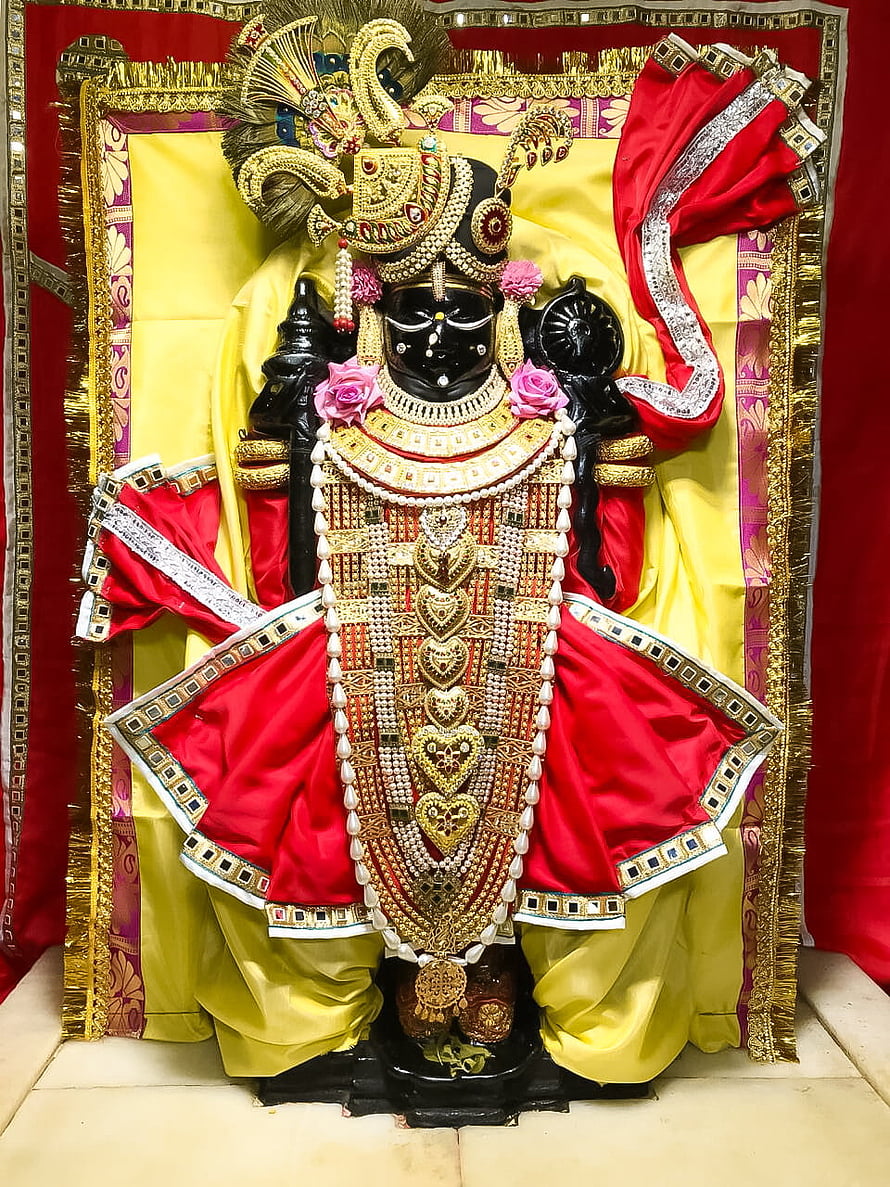 Black Idol of Lord Krishna Adorned with Gold Jewelry and Red Silk Garments HD phone wallpaper