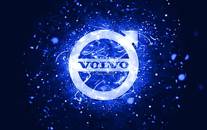 Volvo emblem glowing with electric blue energy and particle effects on a dark abstract background HD wallpaper