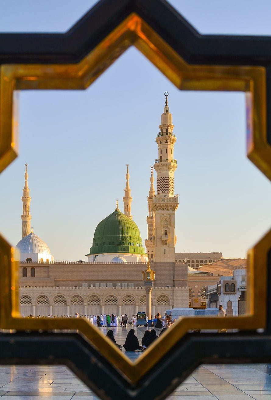 Al-Masjid an-Nabawi in Medina framed by a golden geometric window at golden hour HD phone wallpaper