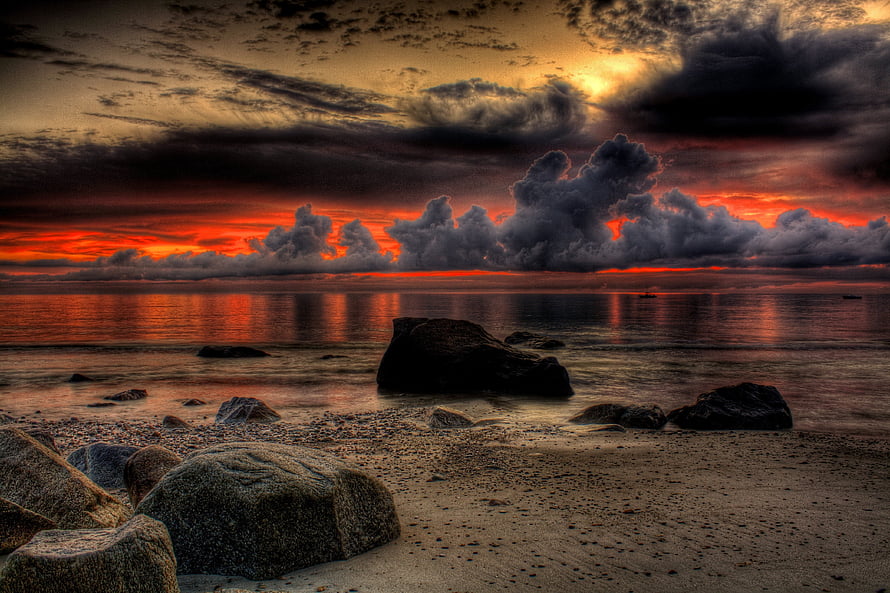 Dramatic Ocean Sunset with Heavy Clouds and Rocky Shoreline HD wallpaper