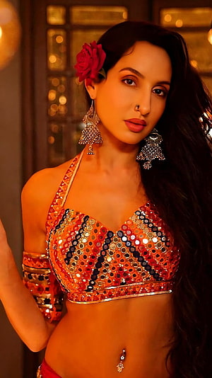 Kiara Advani in a vibrant orange sequined belly dance costume with traditional jewelry and a red flower in her hair HD phone wallpaper