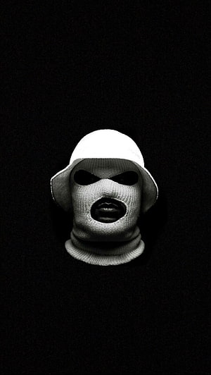 A striking black and white portrait of a person wearing a white knit balaclava and bucket hat against a dark background HD phone wallpaper