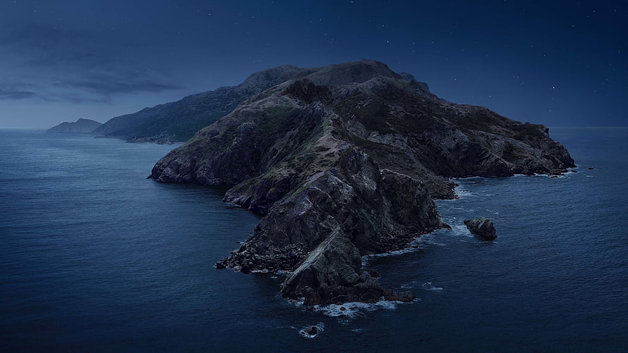 Aerial View of a Rugged Coastal Island at Night Under a Starry Sky HD wallpaper