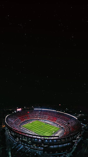 Aerial Night View of a Packed Soccer Stadium with Illuminated Green Pitch and Red Crowd HD phone wallpaper