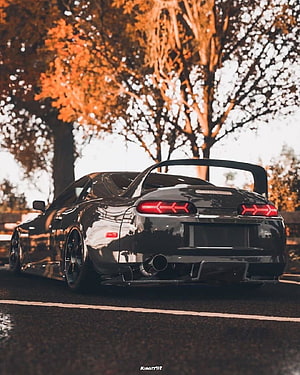 Black Toyota Supra MK4 with large rear wing parked on road under autumn trees HD phone wallpaper