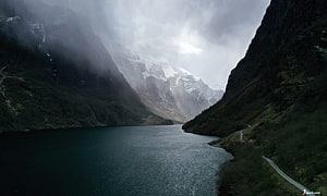 Misty Norwegian Fjord with Snow-Capped Mountains and Dark Water HD wallpaper