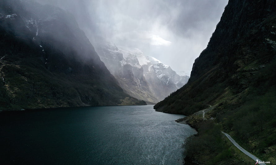 Misty Norwegian Fjord with Snow-Capped Mountains and Dark Water HD wallpaper