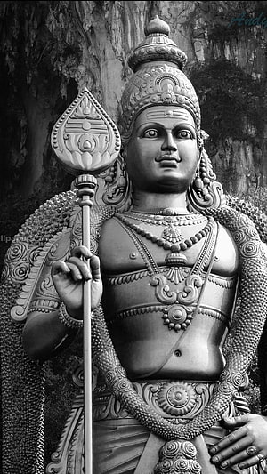 Black and white portrait of a detailed Hindu deity statue holding a staff with ornate jewelry and crown HD phone wallpaper