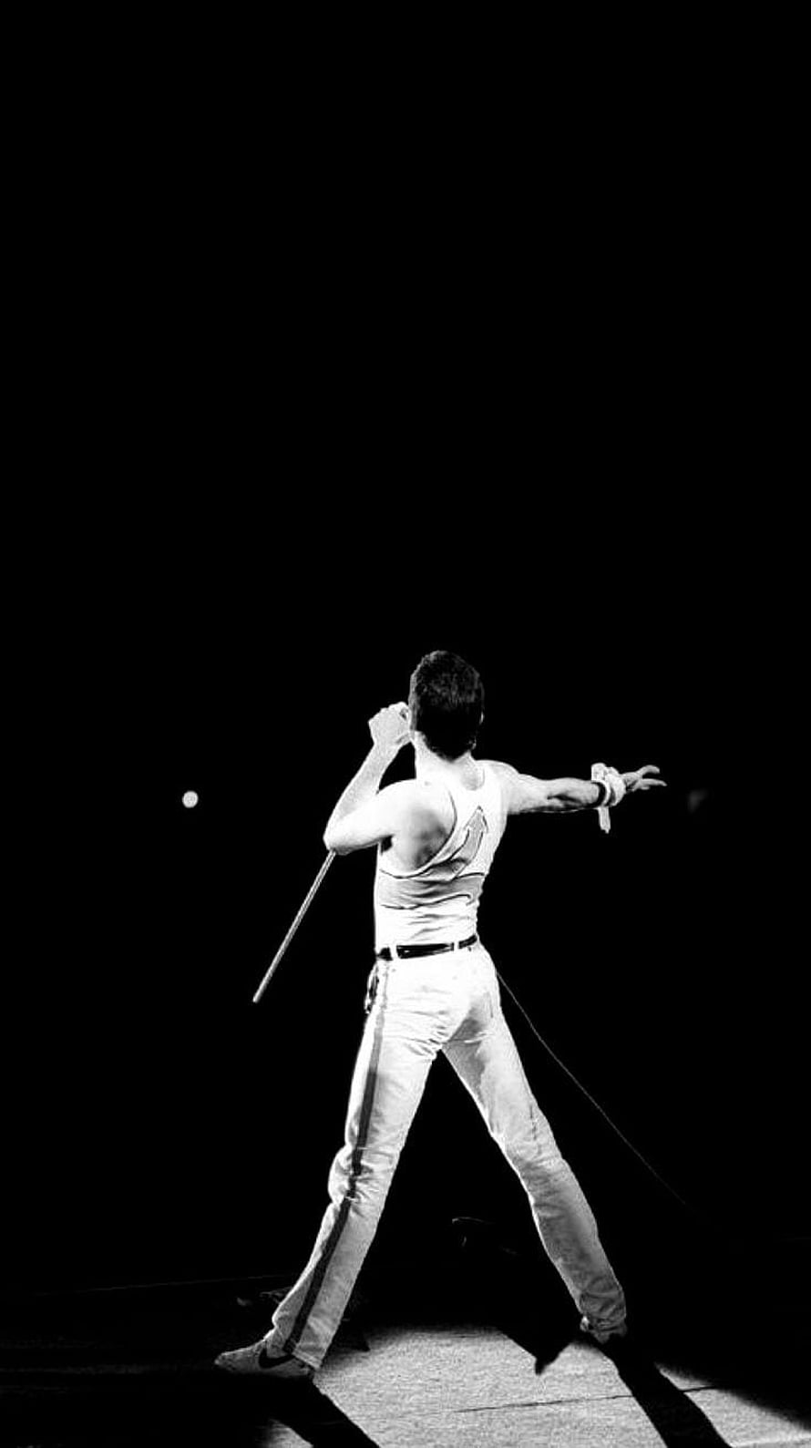 Freddie Mercury performing on stage in a white tank top and trousers HD phone wallpaper