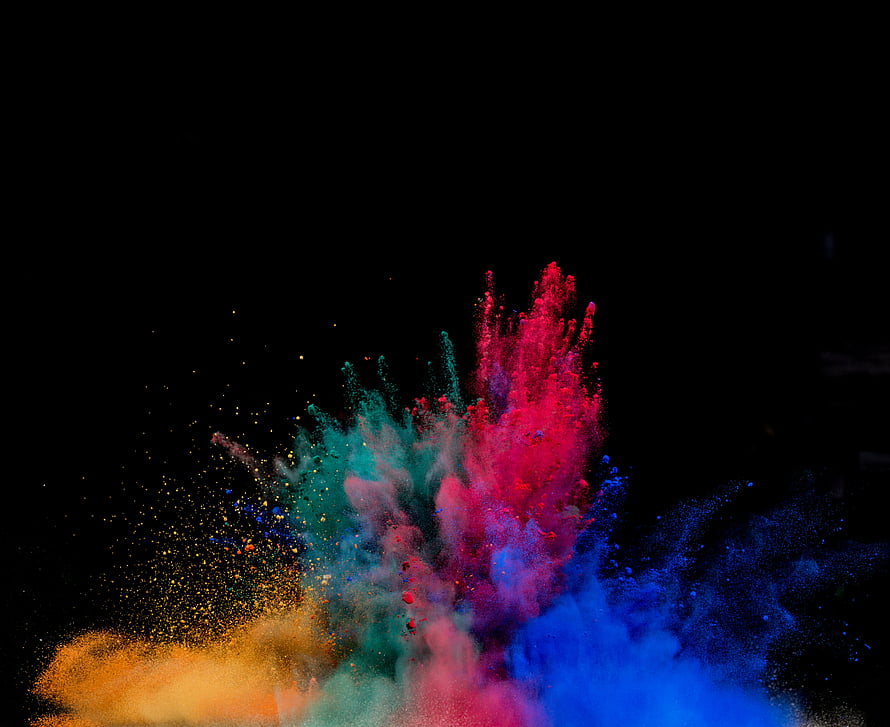 Vibrant multicolored powder explosion bursting against a dark black background HD wallpaper