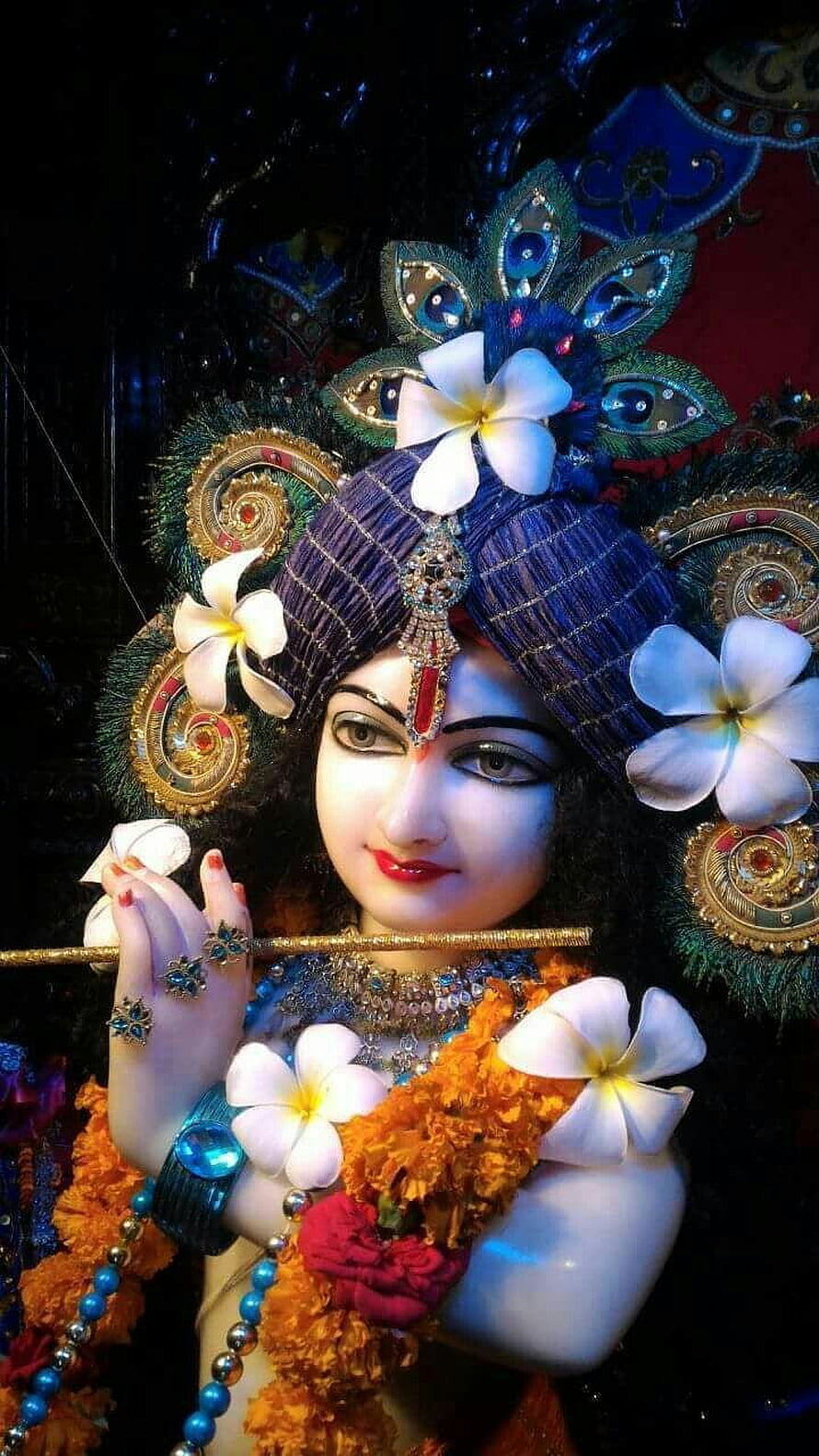 Ornate Krishna Idol Adorned With Marigold Garland And White Plumeria Flowers HD phone wallpaper