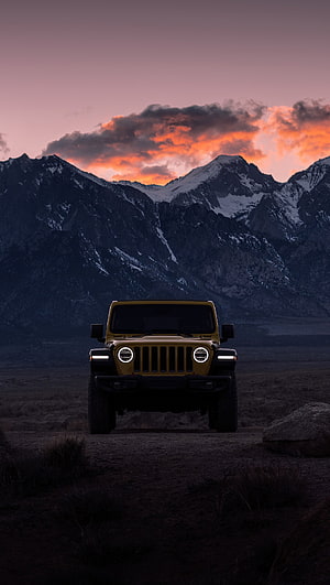 Jeep Wrangler Rubicon parked on a mountain trail at sunset with dramatic alpine peaks in the background HD phone wallpaper