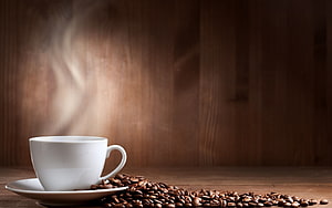 Steaming White Coffee Cup on Wooden Table with Scattered Roasted Beans HD wallpaper