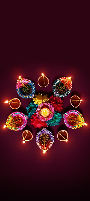 Festive Diwali Diya Lamps and Colorful Flowers Arranged in a Circular Pattern on a Dark Background HD phone wallpaper
