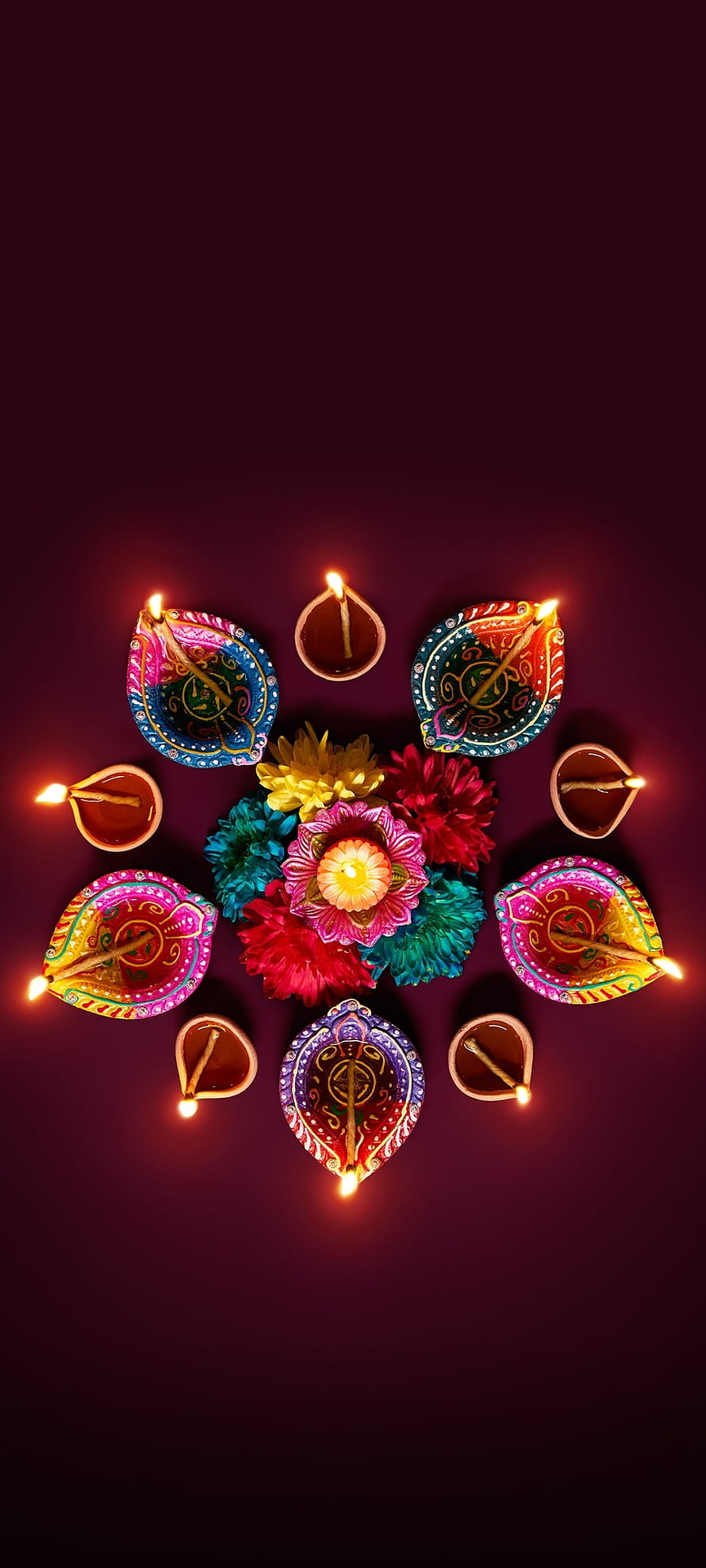 Festive Diwali Diya Lamps and Colorful Flowers Arranged in a Circular Pattern on a Dark Background HD phone wallpaper
