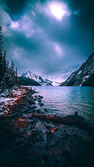 Serene Mountain Lake With Snowy Peaks And Dramatic Cloudy Sky HD phone wallpaper