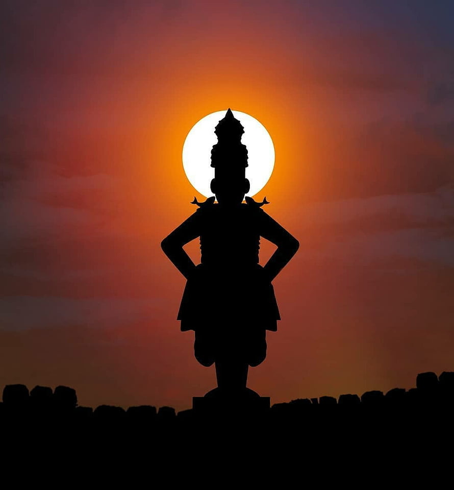 Silhouette of a traditional statue standing against a vibrant orange sunset sky HD phone wallpaper