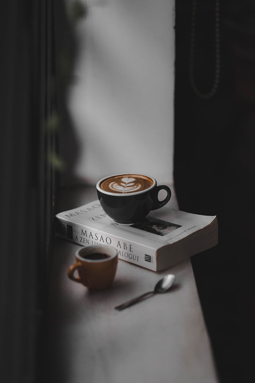 Cozy Latte Art Coffee Cup Resting on a Book by a Window Sill HD phone wallpaper