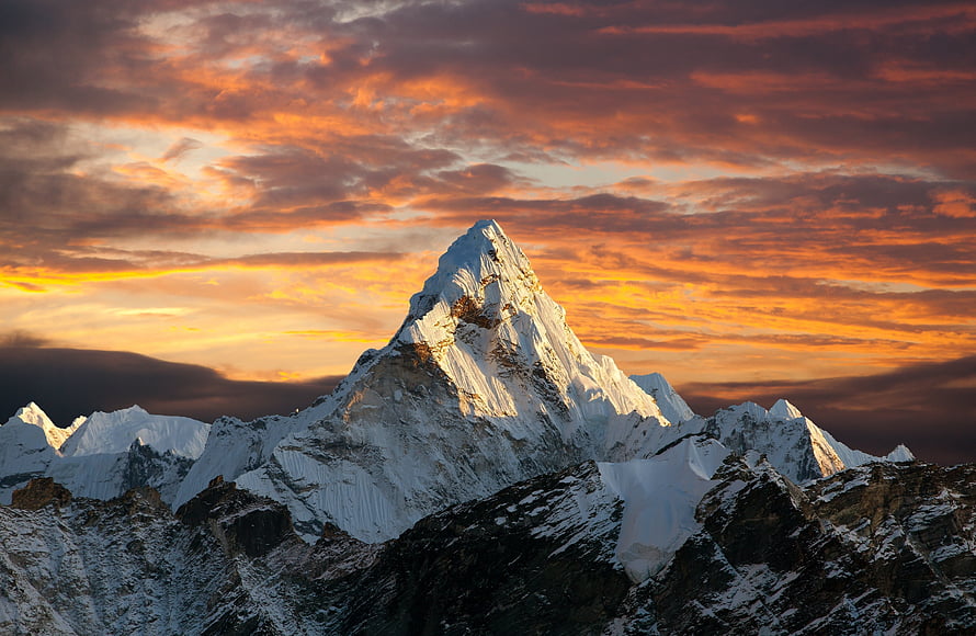 Majestic Snow-Capped Mountain Peak Under a Dramatic Orange Sunset Sky HD wallpaper