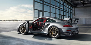 Silver Porsche 911 GT2 RS with Open Door and Rear Wing in Modern Industrial Setting HD wallpaper