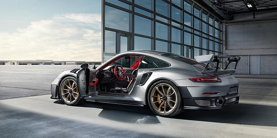 Silver Porsche 911 GT2 RS with Open Door and Rear Wing in Modern Industrial Setting HD wallpaper