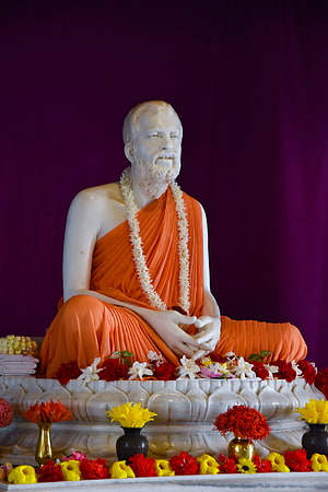 White Statue of Swami Vivekananda in Orange Robes with Flower Offerings HD phone wallpaper