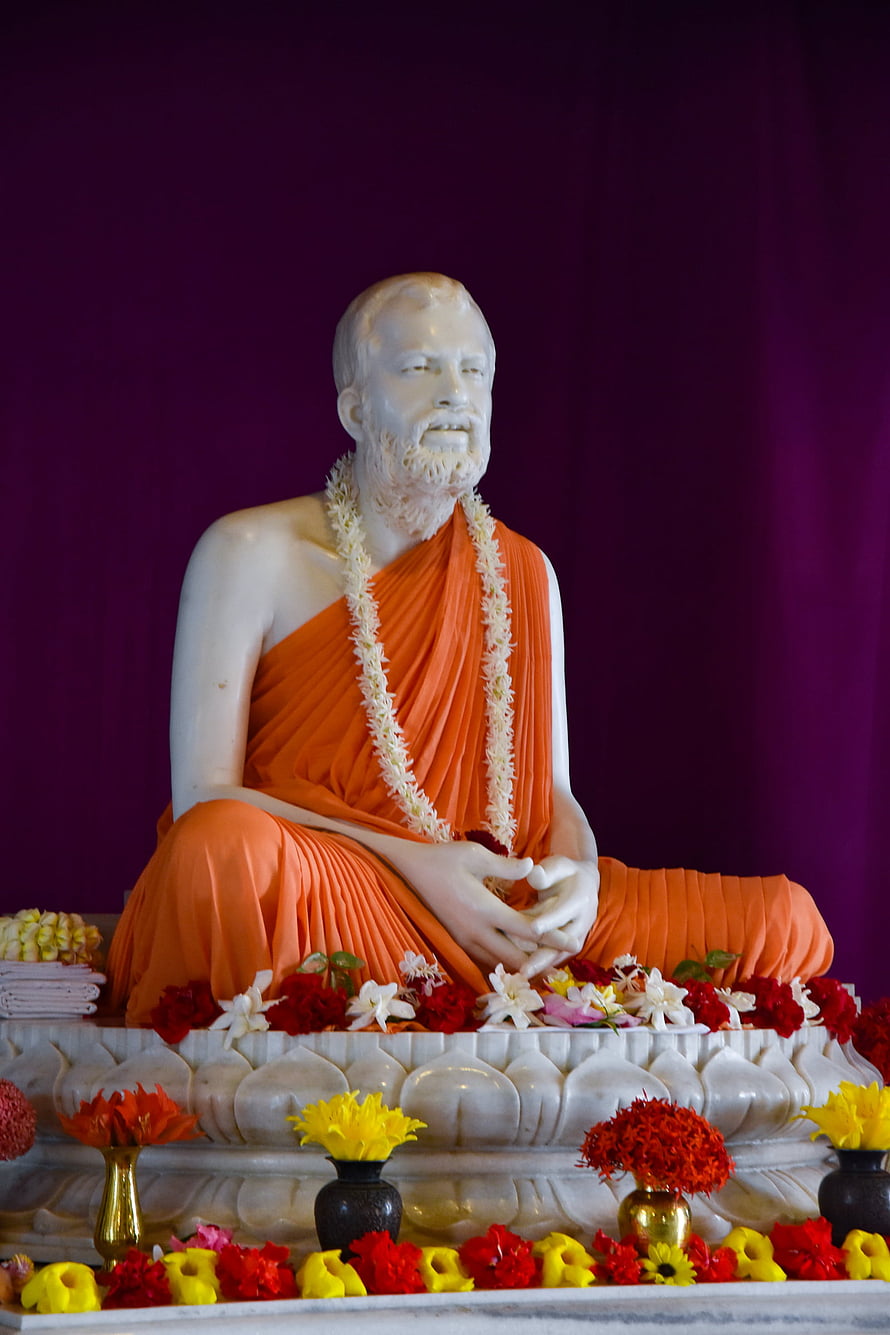 White Statue of Swami Vivekananda in Orange Robes with Flower Offerings HD phone wallpaper