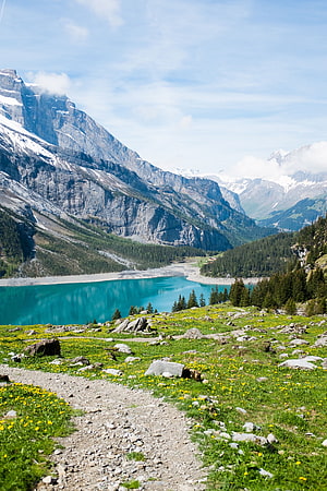 Turquoise Alpine Lake Surrounded by Snow-Capped Peaks and Wildflower Meadows HD phone wallpaper