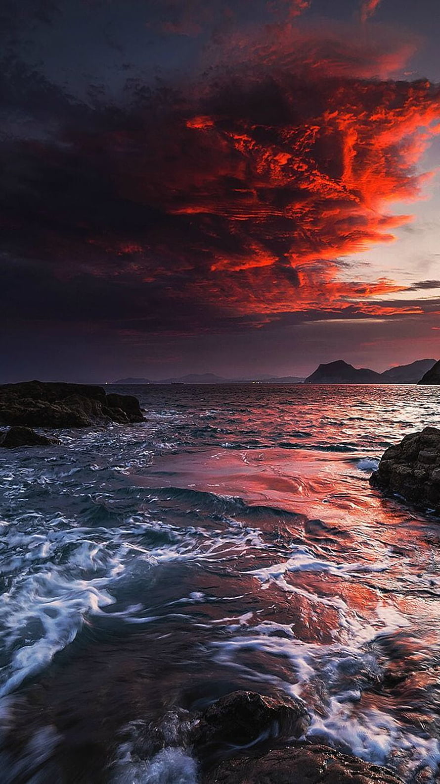Dramatic Crimson Sunset Over Rocky Ocean Coastline with Churning Waves HD phone wallpaper