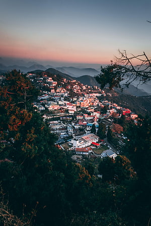Glimmering Hillside Town at Sunset with Misty Mountain Layers HD phone wallpaper