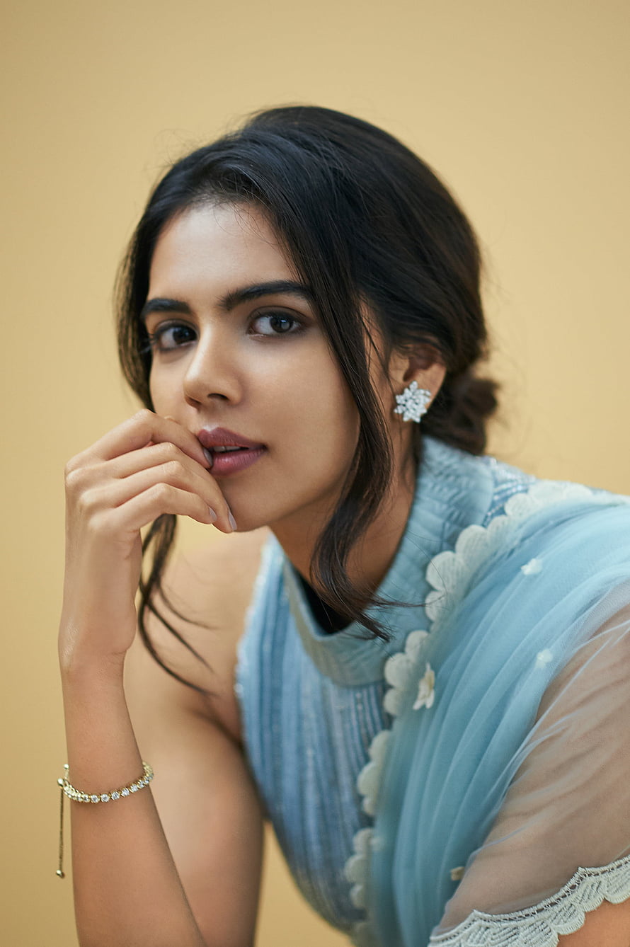 Kalyani Priyadarshan in a light blue embroidered outfit with delicate jewelry against a warm beige backdrop HD phone wallpaper